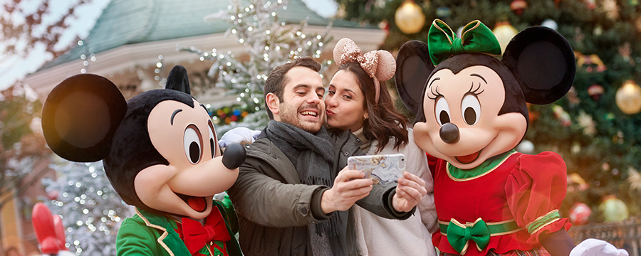 Couple taking Christmas selfie with Mickey and Minnie