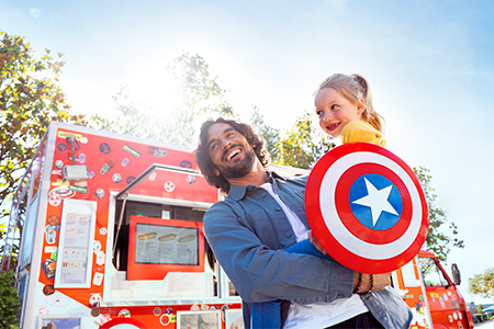 Family with Captain America shield in front of Marvel Avengers Campus food truck