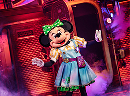 Minnie Mouse in a colourful dress performing on stage at Minnie’s Dream Factory in Disneyland Paris.
