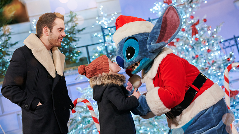 Father and son meet Stitch dressed as Santa, as son kisses Stitch on the nose