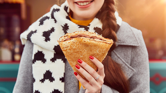 Guest holding a chocolate crêpe at Les Chalets Gourmands winter market in Disneyland Paris