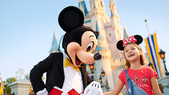 Young girl wearing Minnie ears laughing with Mickey at Magic Kingdom