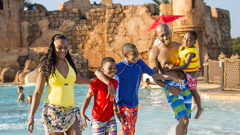 Family going for a dip in the pool at Disney's Caribbean Beach Resort
